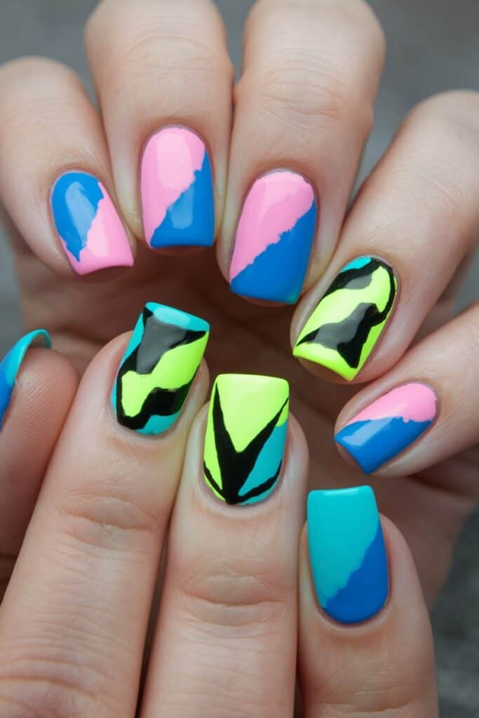 Color-block acrylic nails in electric pink, blue, lime green, and black graphic designs.
