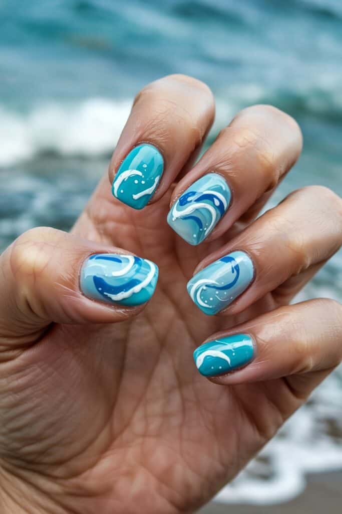a hand with painted nails with ocean nail art theme.