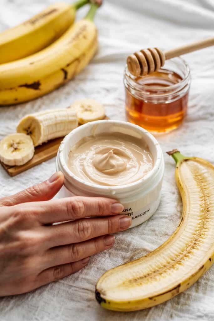 (Banana-Honey Smoothing Mask):
"Smooth banana mask in a white bowl with sliced bananas and honey jar in the background."
