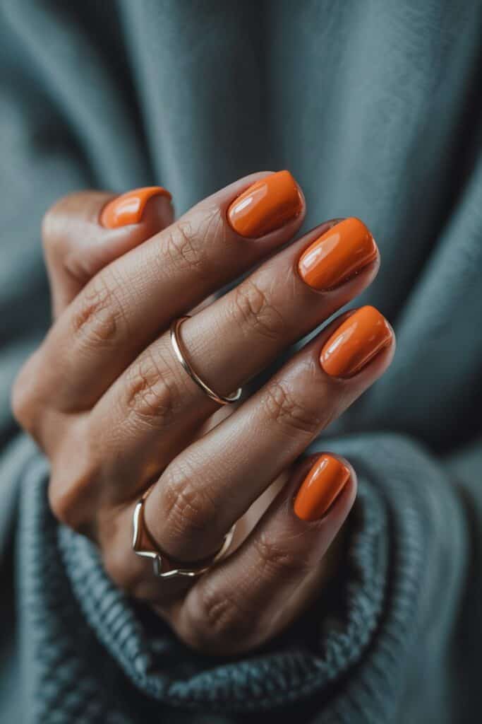 1. **Classic Glossy Burnt Orange**: Glossy burnt orange manicure on long almond-shaped nails showcasing a rich autumn color.
