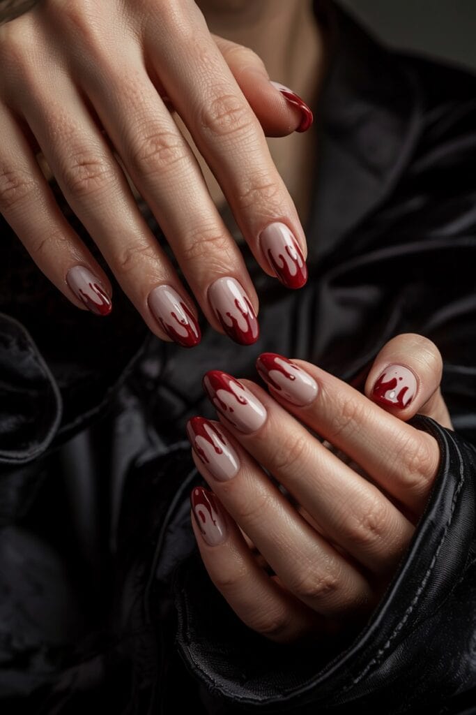 Short nude nails with oxblood red drip tips creating a subtle vampire-inspired Halloween look.
