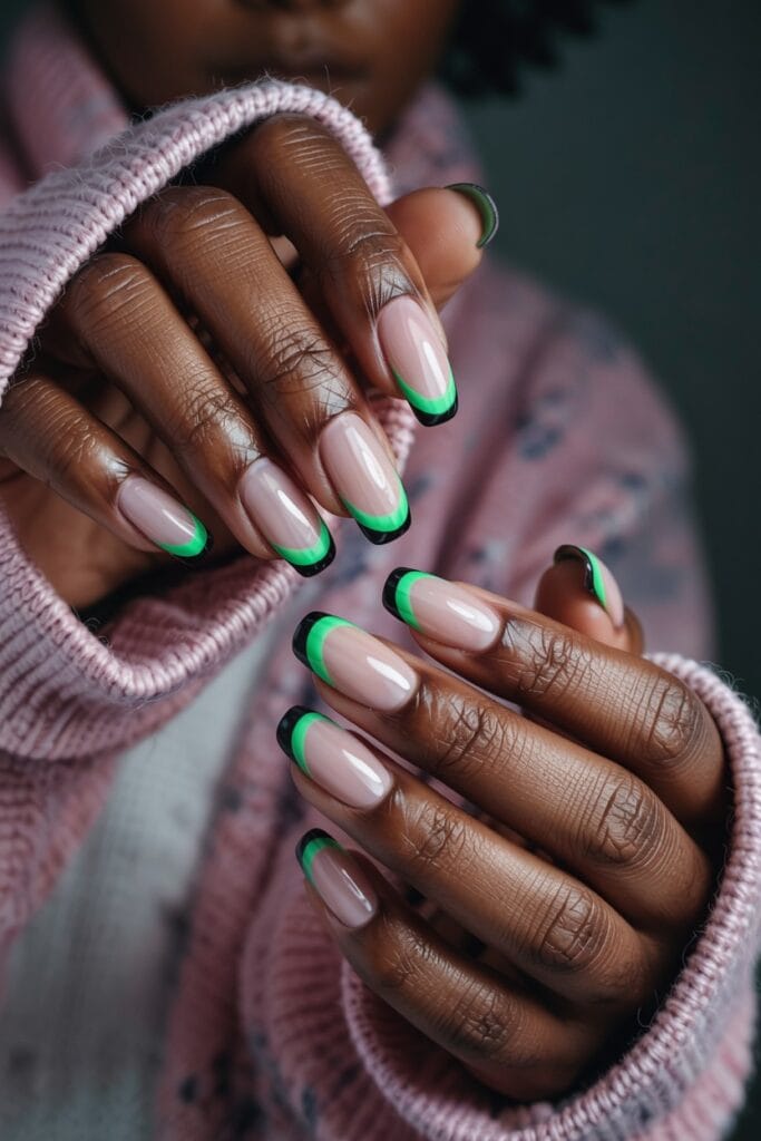 Short nails with witch-green French tips and thin black detail line for a Halloween-inspired manicure.
