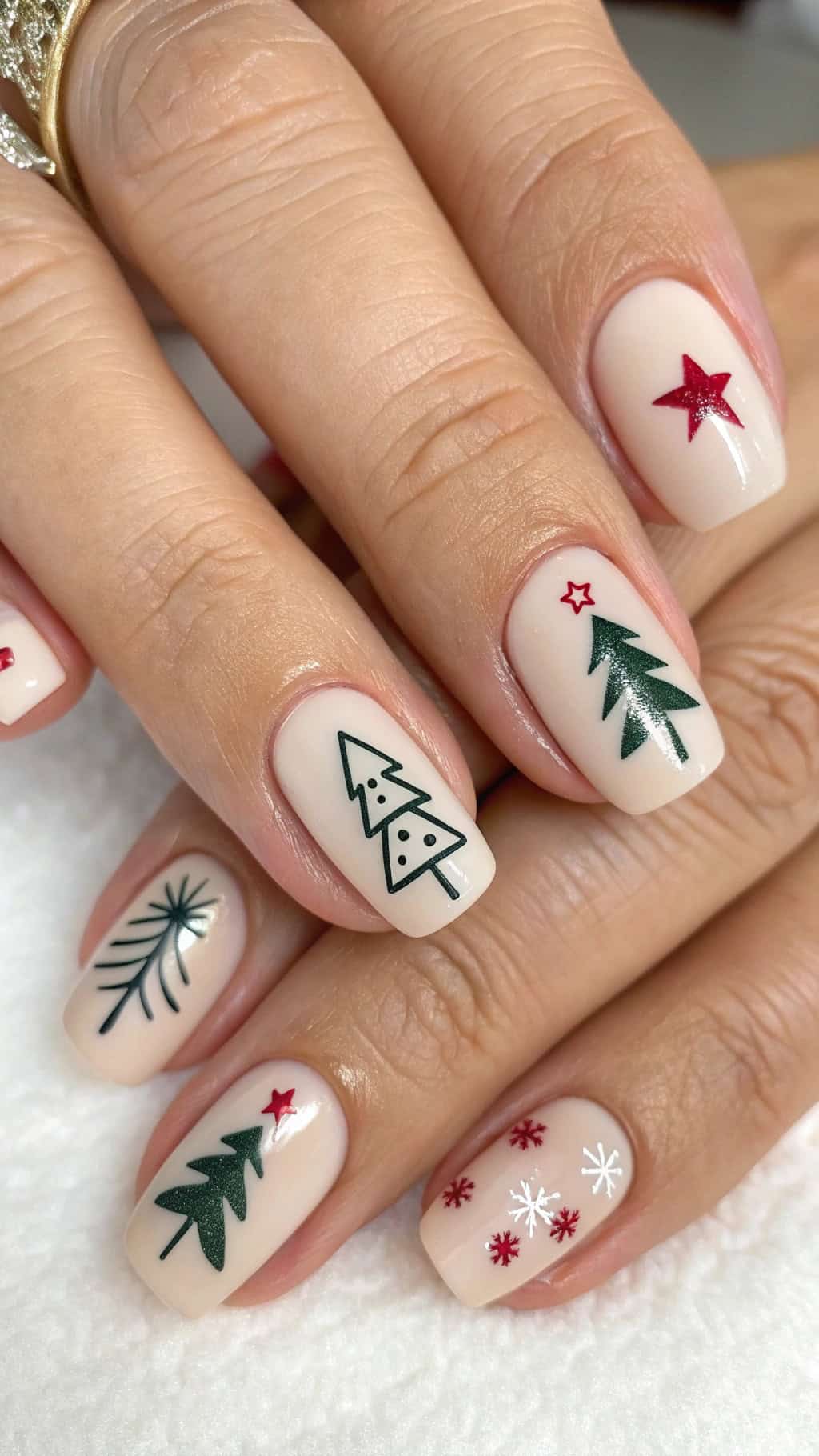 Minimalist Christmas nail designs featuring trees, stars, and snowflakes on a nude background.