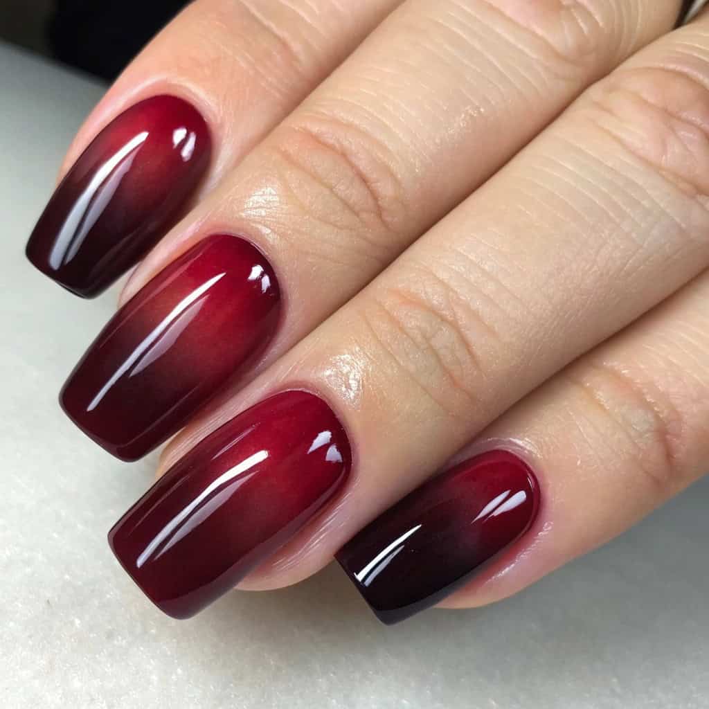 Ombre dark cherry red nails with a gradient effect from dark red to light pink.