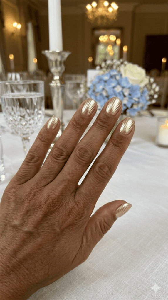Deep rich skin tone with metallic champagne gold burst nail design fanning from the cuticle, indoor wedding reception lighting, luxury aesthetic.